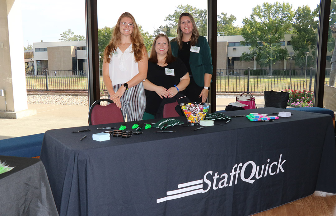 Employees from StaffQuick welcome attendees to their table.